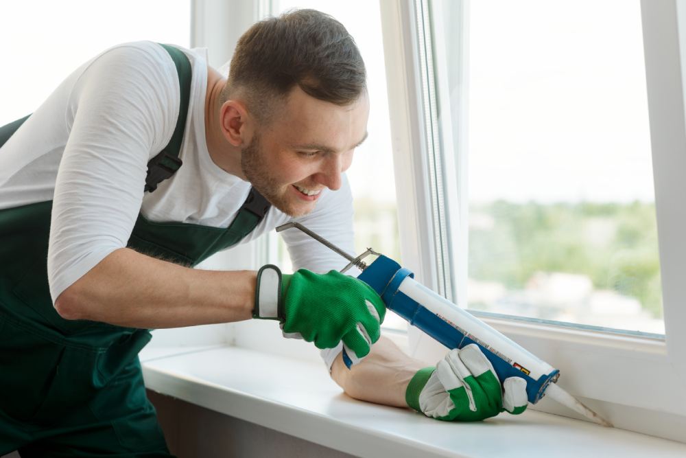 Man applying silicone sealant between window sash and sill. Home repair and renovation, handyman for an hour service.